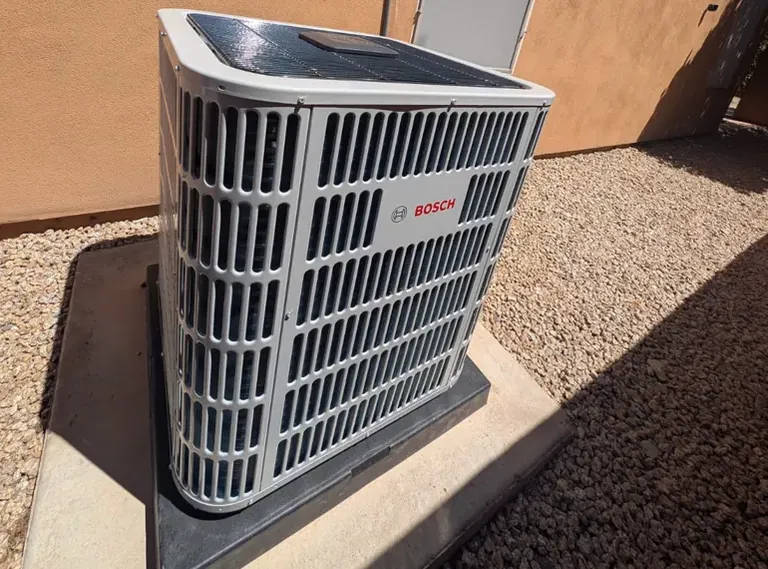 New air conditioning condenser on a pad in a gravel side yard in Glendale, AZ